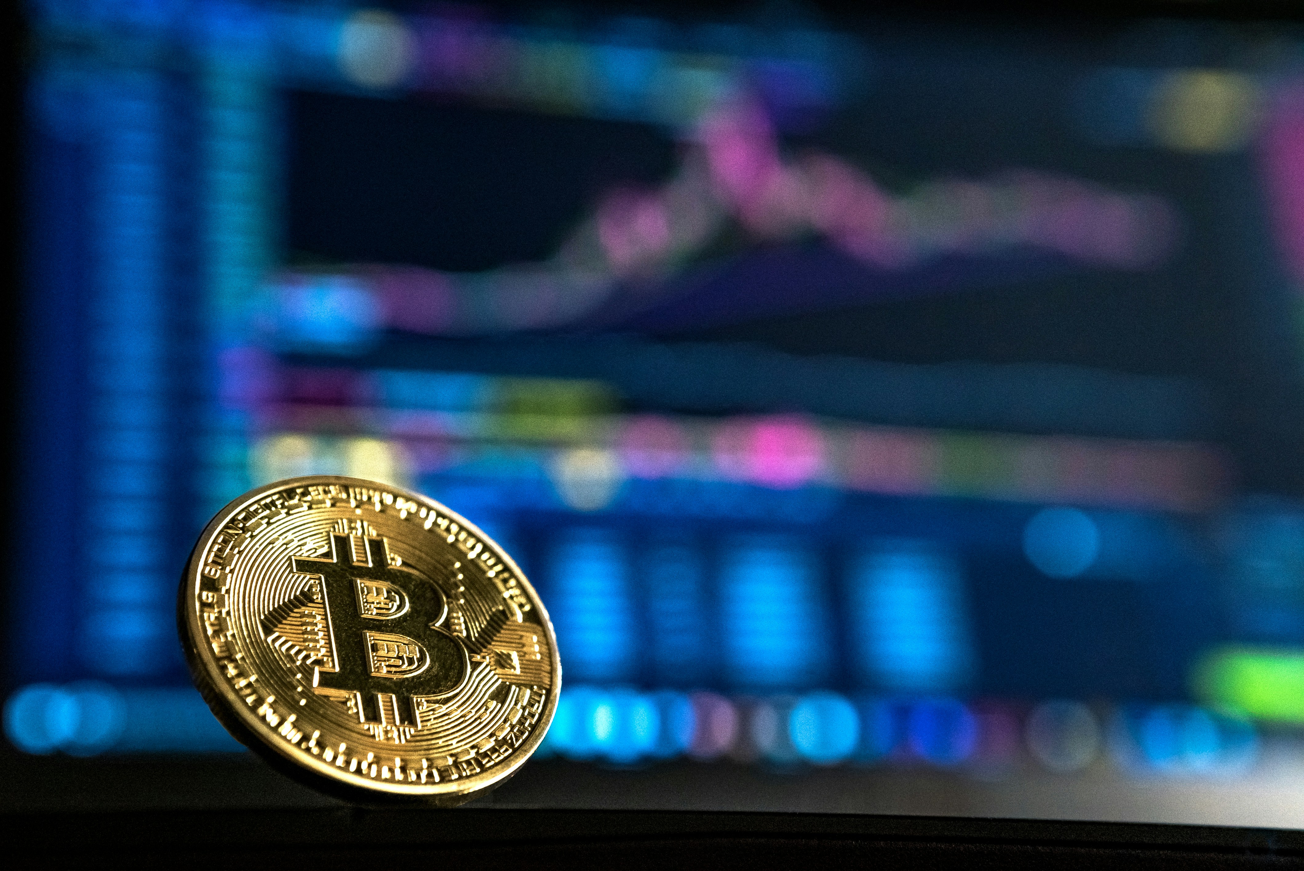 Computer screen with a physical representation of a Bitcoin leaned against it
